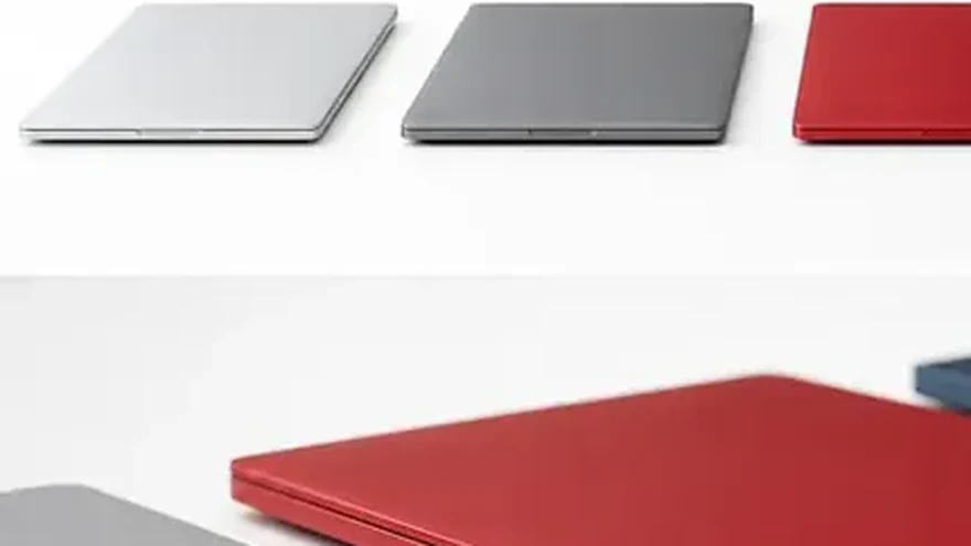 Several distinct closed laptops arranged in a row on a table, each a different colour